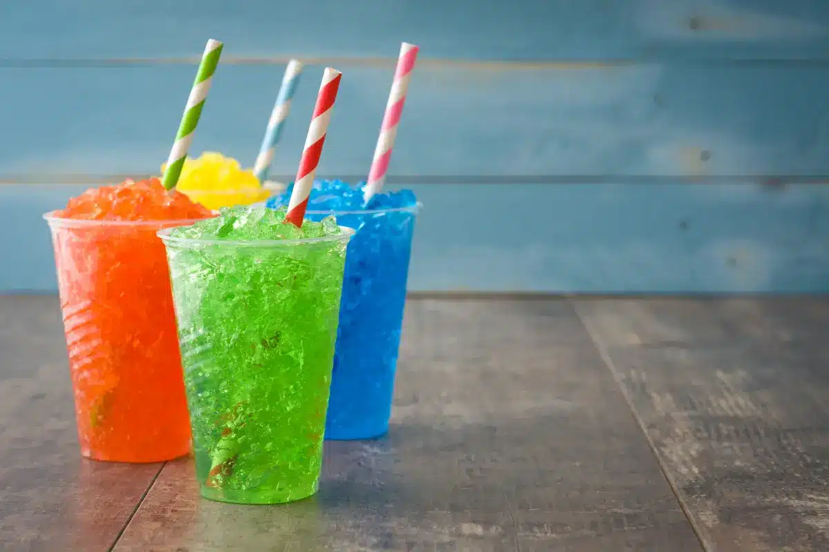 Vibrant homemade slushie with orange, pineapple, and strawberry layers on a sunny day.