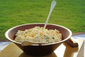 Bowl of creamy Hawaiian Macaroni Salad with shredded carrots and onions.