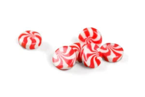 Homemade red and white striped peppermint candies on a wooden background