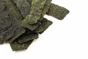 Crispy homemade seaweed snacks with sea salt on a rustic wooden plate.