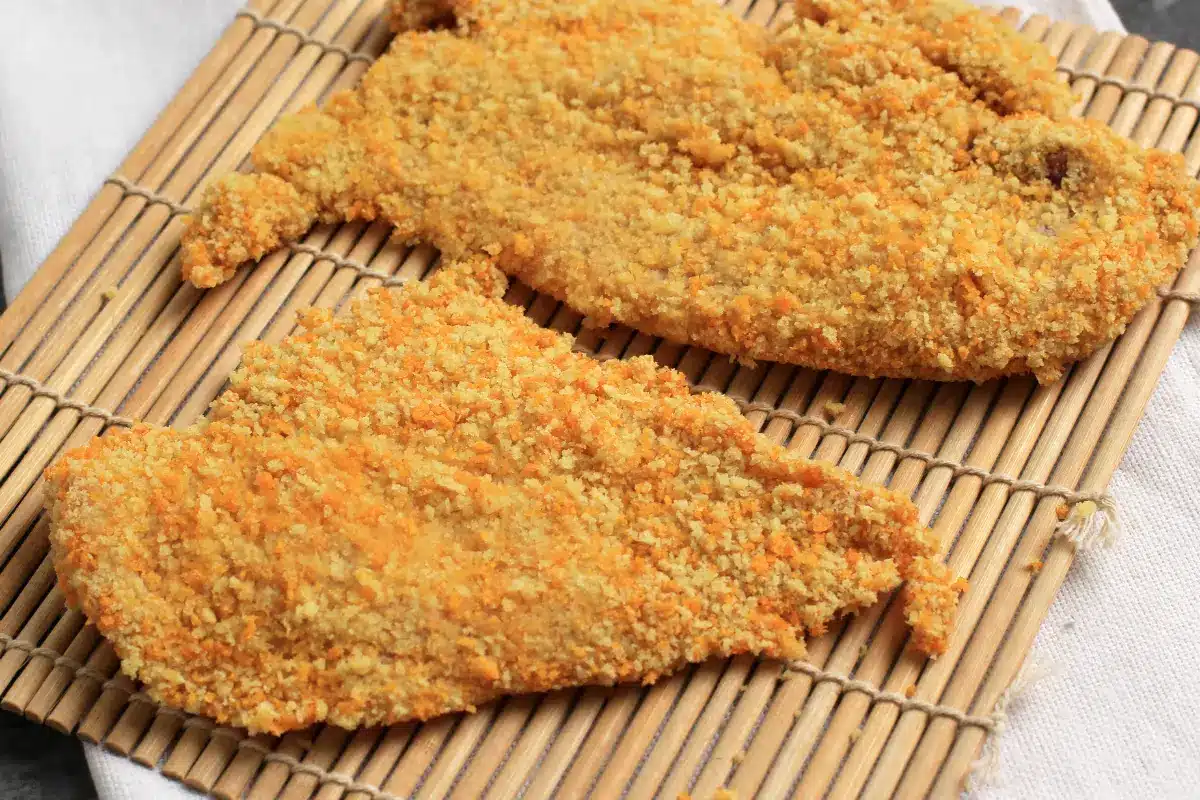 Golden crispy chicken cutlets on a plate with parsley and lemon.