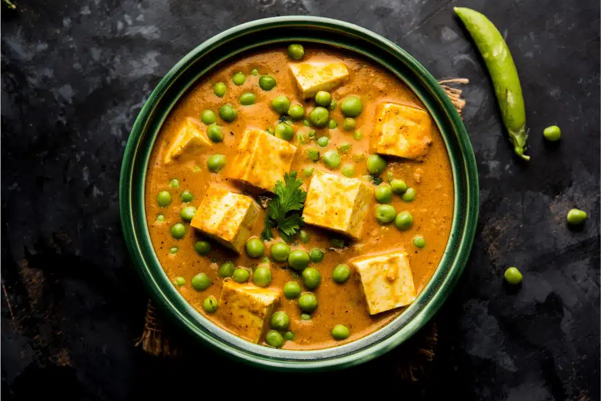 A bowl of Caribbean Style Stewed Pigeon Peas with rice and plantains on the side.