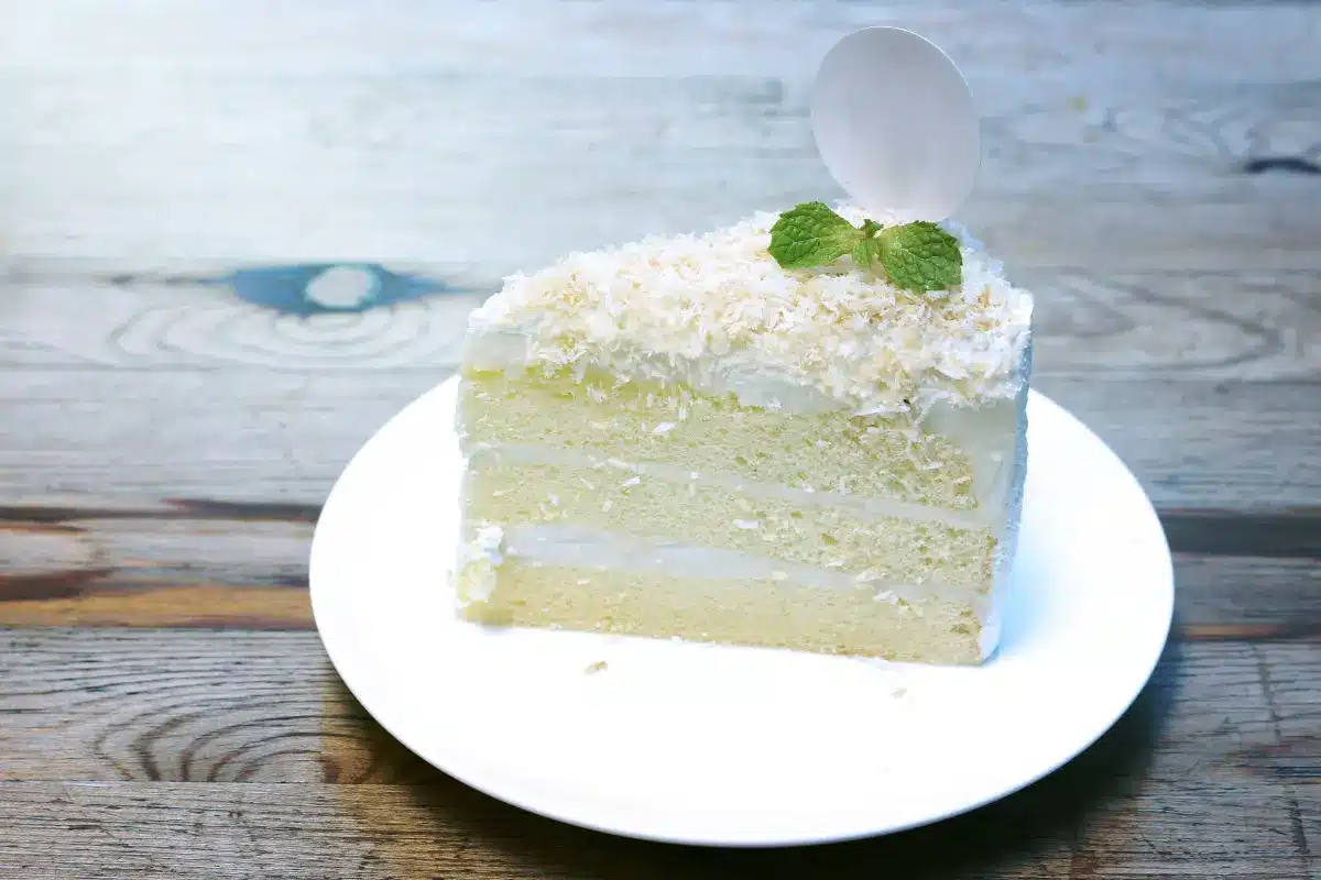 A beautifully layered and frosted coconut cake topped with toasted coconut flakes