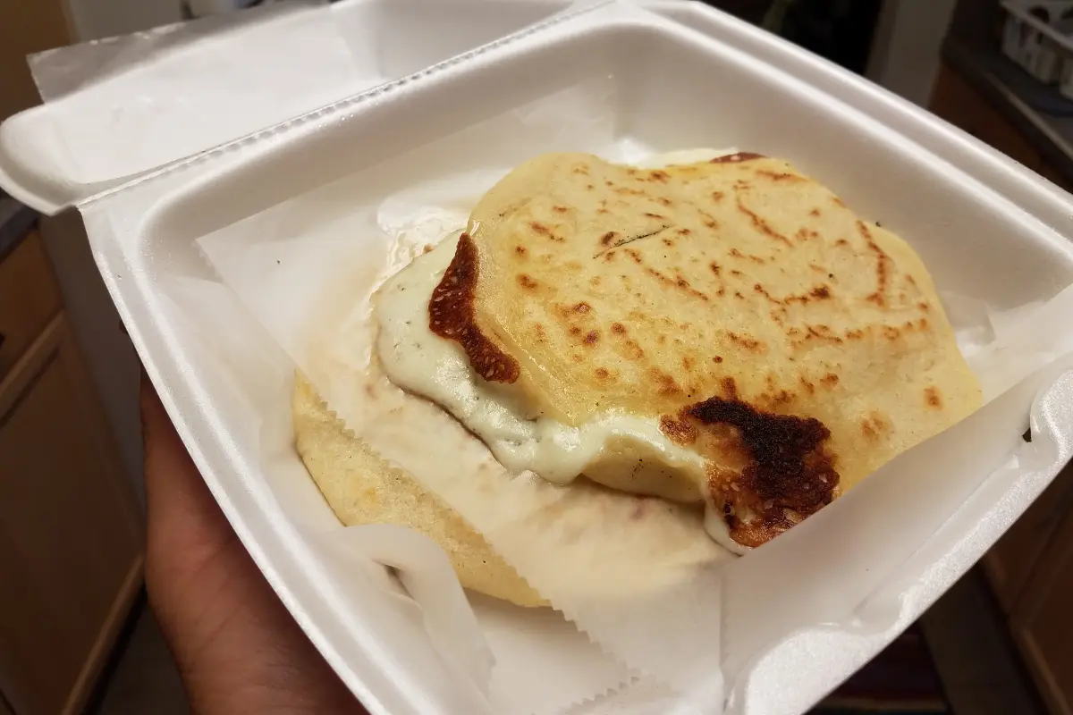 Homemade papusas with curtido on a serving plate.