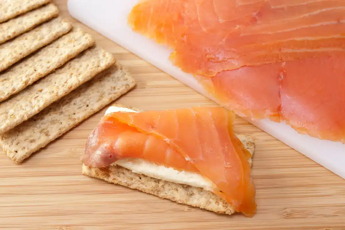 Smoked cream cheese on a wooden board with salsa and crackers.