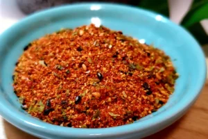 Minimalist Togarashi composition with a glass jar, red chili peppers, sesame seeds, and dried orange peel on a sleek counter.