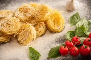 A plate of capellini pasta with garlic, lemon, and Parmesan, garnished with fresh herbs.