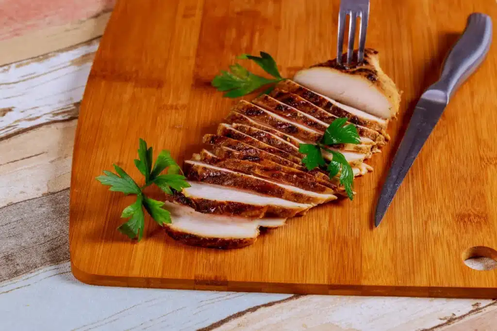 Juicy smoked chicken breast on a wooden cutting board with herbs