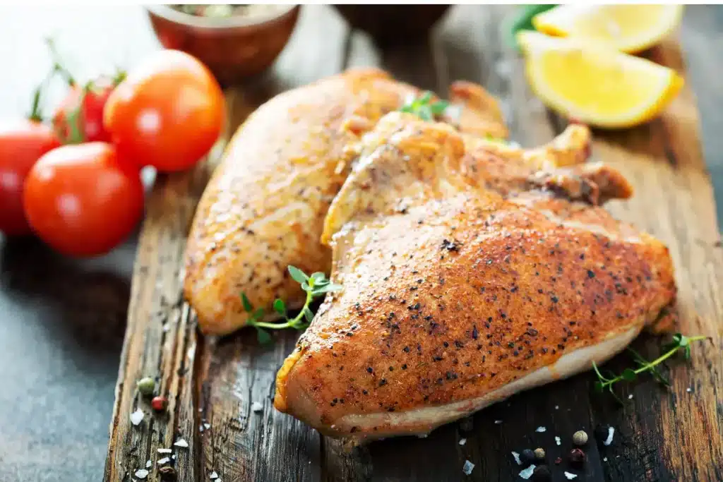 Juicy smoked chicken breast on a wooden cutting board with herbs.