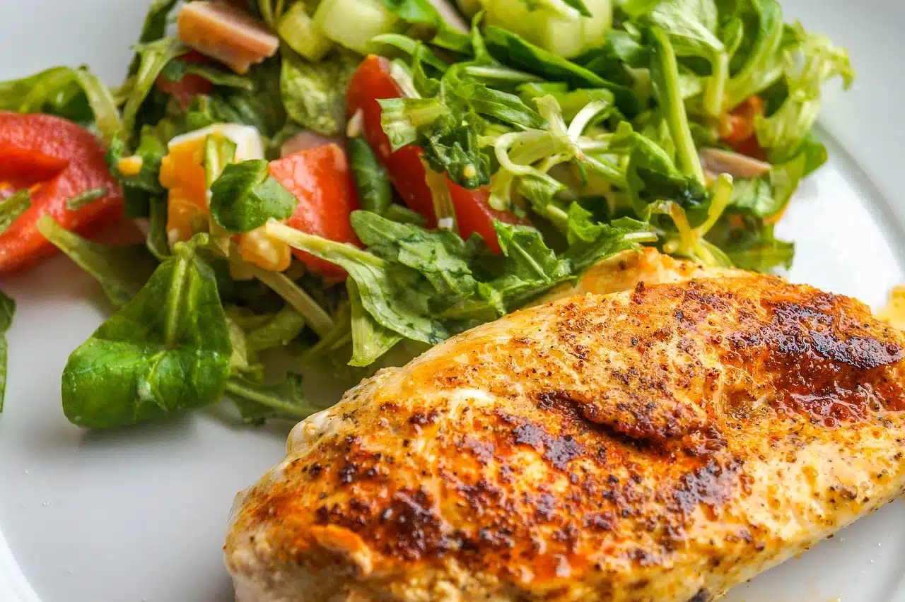 Juicy smoked chicken breast on a wooden cutting board with herbs.