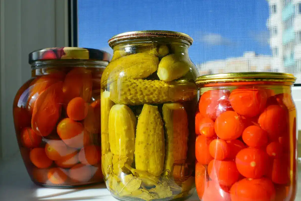 Vibrant chamoy pickles in a jar with chamoy sauce and Tajin