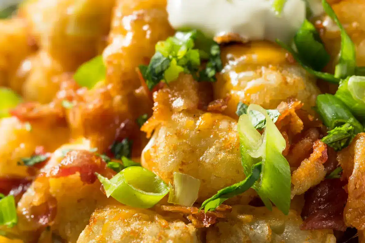 A colorful serving of loaded tater tots with toppings.